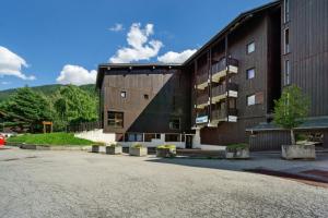 a large brown building with a parking lot in front of it at Les Airelles 32 in Villarodin-Bourget