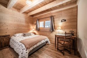 a bedroom with wooden walls and a bed and a desk at Le Chat Perché in Bernex