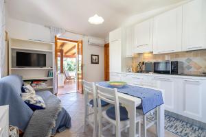 a kitchen with white cabinets and a table with chairs at Casa con terrazza nella Pineta in Codaruina +21 photos