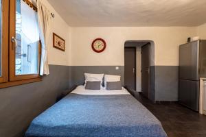 a bed in a room with a clock on the wall at Joli Appartement Sur Le Bois in Aigueblanche