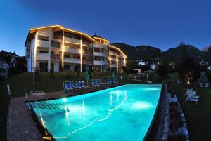 a hotel with a swimming pool in front of a building at Residence Nussbaumer in Siusi