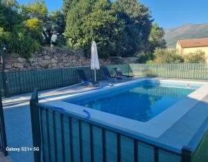 a swimming pool with two chairs and an umbrella at Casa Rural El Barranco in Mombeltrán