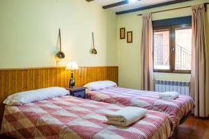 two beds in a room with a window at Casa Rural El Barranco in Mombeltrán +26 photos