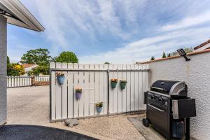 a grill sitting next to a white fence with potted plants at Studio chez Brigitte à Audenge in Audenge