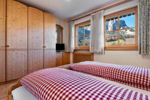 a bedroom with a bed with a red and white checked blanket at Apartments Campagnola in Badia