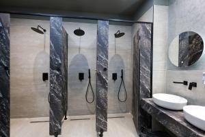 a bathroom with a shower with two sinks and mirrors at Grand Hostel Berat in Berat +77 photos