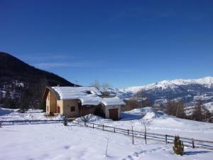 a house covered in snow with mountains in the background at Chalet St Victoire - Les Orres in Les Orres