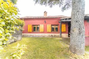 a red house with yellow windows and a tree at El Colono El uncar in Castrejón de la Peña