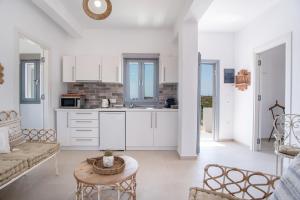 a kitchen and living room with white cabinets and a table at Villa Anastasio in Kampos Paros