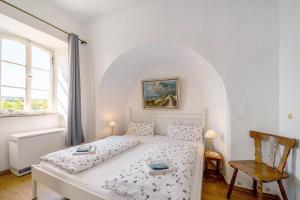 a bedroom with a white bed and a chair at Ferienwohnung Abtei Klosterhof in Maring-Noviand