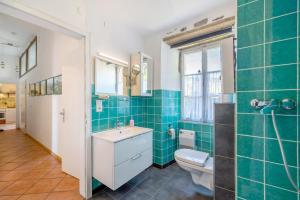 a bathroom with a toilet sink and green tiles at Ferienwohnung Abtei Klosterhof in Maring-Noviand
