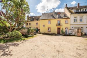 an empty driveway in front of a yellow house at Ferienwohnung Abtei Klosterhof in Maring-Noviand