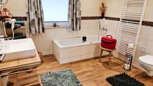 a bathroom with a white tub and a red bag on a chair at Franz Josefs Wald-Chalets in Untergriesbach +32 photos