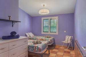 a bedroom with purple walls and a bed and a window at Bungalow El Caserío De Merengue in San Bartolomé +18 photos