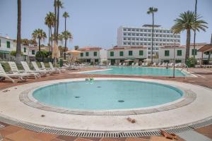 a large swimming pool with chairs and a building at Bungalow El Caserío De Merengue in San Bartolomé