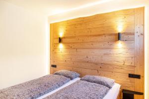 two beds in a room with a wooden wall at Ammerstube Oberammergau in Oberammergau