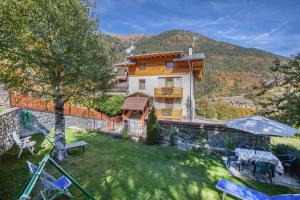 a house with a yard with chairs and a building at Casa Penasa App 3 in Commezzadura