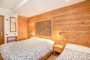 two beds in a room with wooden walls at Casa Penasa App 3 in Commezzadura