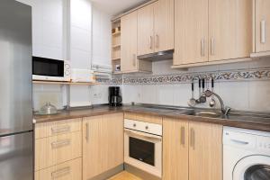 a kitchen with wooden cabinets and a sink and a dishwasher at Vejer 1 - Andalmar in Vejer de la Frontera