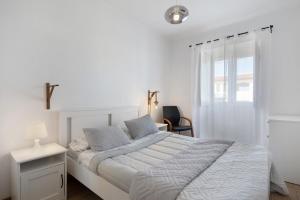 a white bedroom with a bed and a window at Nuria House in Praia da Vitória