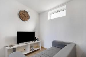 a living room with a couch and a clock on the wall at Nuria House in Praia da Vitória
