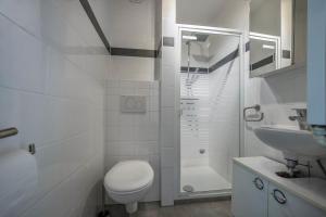 a white bathroom with a toilet and a sink at Braunlageblick in Braunlage +11 photos