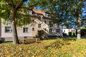 a house with a bench in front of a tree at Ferienwohnungen Neuseenland in Rötha