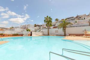 a large swimming pool with palm trees and buildings at Casa Los Caideros in Los Caideros