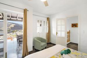 a bedroom with a bed and a chair and a window at Casa Los Caideros in Los Caideros