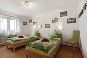 a bedroom with two beds and a green chair at Ferienwohnungen Hog , Ringsheim in Ringsheim