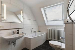 a bathroom with a sink and a tub and a toilet at Ferienwohnungen Hog , Ringsheim in Ringsheim +65 photos