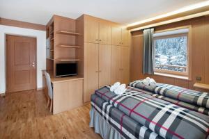a bedroom with two beds and a desk and a window at Guesthouse Canazei Cozy 2-Bedrooms in Canazei