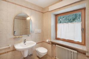 a bathroom with a sink and a toilet and a window at Guesthouse Canazei Cozy 2-Bedrooms in Canazei +15 photos