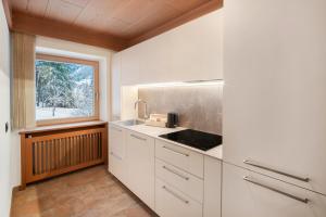 a kitchen with white cabinets and a window at Guesthouse Canazei Cozy 2-Bedrooms in Canazei