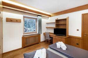 a room with a bed and a desk and a window at Guesthouse Canazei Cozy 2-Bedrooms in Canazei