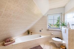 a bathroom with a tub and a toilet and a window at Ferienwohnung An der Haferkoppel in Groß Kussewitz +24 photos