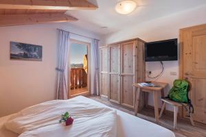 a bedroom with a bed and a desk and a television at Schildberghof Panorama in Kastelruth