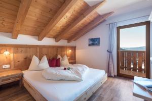 a bedroom with a large white bed with a window at Schildberghof Panorama in Kastelruth