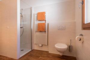 a bathroom with a toilet and a shower with orange towels at Schildberghof Panorama in Kastelruth +35 photos
