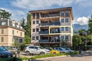 a tall building with cars parked in a parking lot at City Apartment Flora in Merano