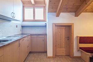 a kitchen with wooden cabinets and a sink and a door at Schildberghof Panorama in Kastelruth