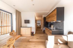 a kitchen with white walls and wooden floors at Sonnleiten Sonnenparadies in Collepietra
