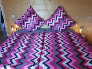 a bed with a pink and white comforter and pillows at Ferienhaus Wolfshütte in Hillesheim