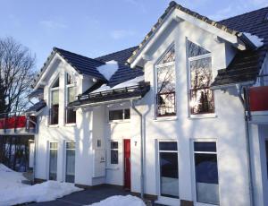 a white house with a red door in the snow at Ferienwohnung Viadukt in Willingen