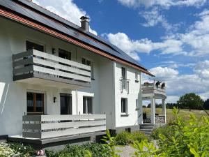 a white house with a balcony on the side at Ferienwohnung Karbachtal in Wangen im Allgäu