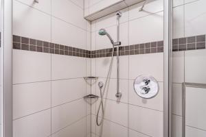 a shower in a bathroom with white tiles at Ferienwohnung Viadukt in Willingen +18 photos