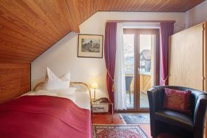 a bedroom with a bed and a chair and a window at Hotel Bären - drei Sterne in Bernau im Schwarzwald