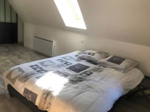 a bed in a white room with a window at Appartement duplex 180m² in La Bourboule +3 photos