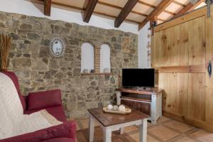 a living room with a tv and a stone wall at Casas Alfonso y Laura in Conil de la Frontera
