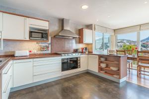 a kitchen with white cabinets and a large window at Villa Almeda in Port d'Andratx